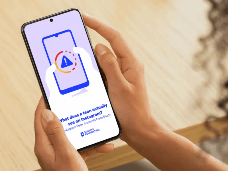 Person holding a smartphone displaying a screen with a warning icon inside an Instagram-style loading ring. The text on the screen reads: 'What does a teen actually see on Instagram? Instagram Teen Accounts Case Study' with the 5Rights Foundation logo beneath it.